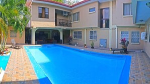 Un edificio de dos plantas con piscina, mobiliario exterior y balcón.