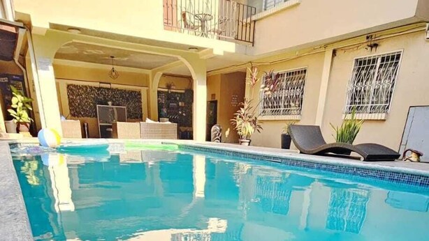 Una piscina con solárium empinado, rodeada por un edificio con balcones y barandillas.
