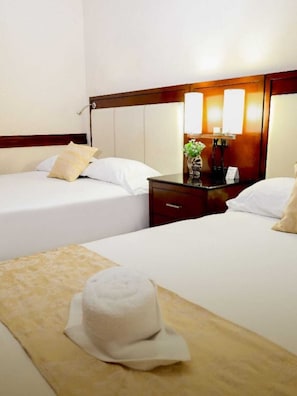 Ein Hotelzimmer mit zwei Betten, einem Nachttisch, einer Lampe und einer dekorativen Vase.
