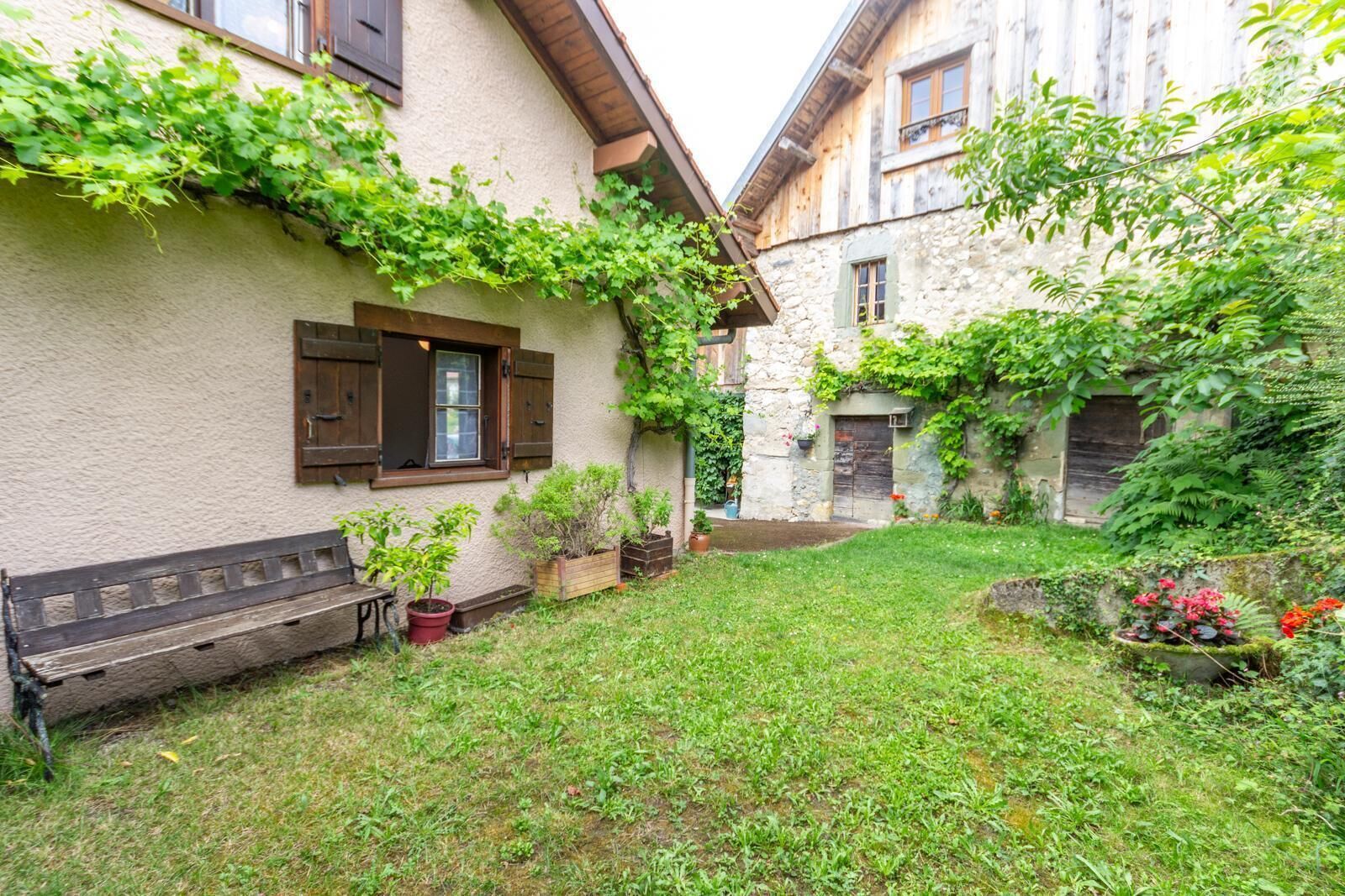 A courtyard with a grassy area, a wooden bench, and potted plants.