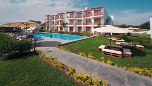 A hotel with a swimming pool, outdoor seating, and a well-maintained lawn. - Hotel La Colina Live the experience among dunes and nature (Cerro Prieto)
