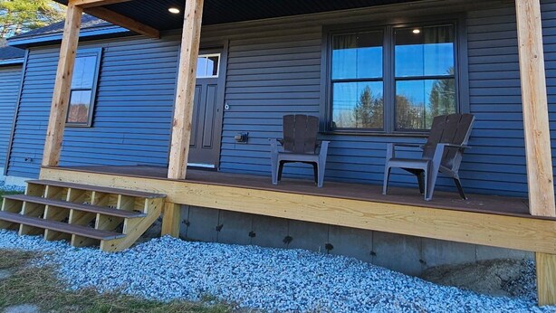 Une cabane en bois dotée d’un porche couvert, d’une fenêtre offrant une belle vue et d’une petite terrasse.