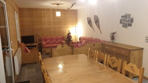 Ein gemütlicher Essbereich mit Holztisch und -stühlen, einem Fernseher und einem Weihnachtsbaum.