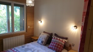 Ein gemütliches Schlafzimmer mit einem Holzkopfende, einem großen Fenster und zwei Nachttischlampen.