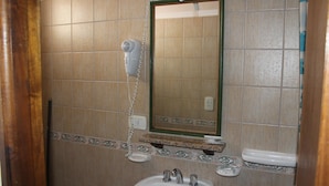 Un baño con lavamanos, secador de pelo y espejo.