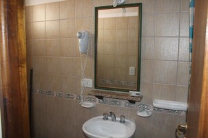 Un baño con lavamanos, secador de pelo y espejo.