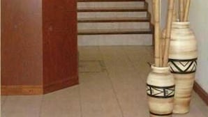 Zona de recepción con mostrador, sillas, una escalera y jarrones decorativos de bambú.
