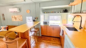 Une cuisine de taille réduite, dotée de plans de travail en bois, d’un four à micro-ondes et d’un évier.
