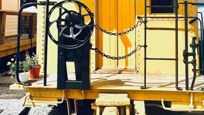 Un wagon de queue jaune, avec une porte, une petite fenêtre et une chaîne.