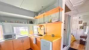 Une cuisine compacte avec des meubles en bois, un four à micro-ondes encastré, un évier et un lave-vaisselle.