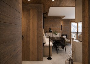 Interior de madeira com área de refeições, um sofá e vista para montanhas pela janela.