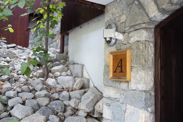 A stone wall with a wooden door and a sign with the letter 'A'.
