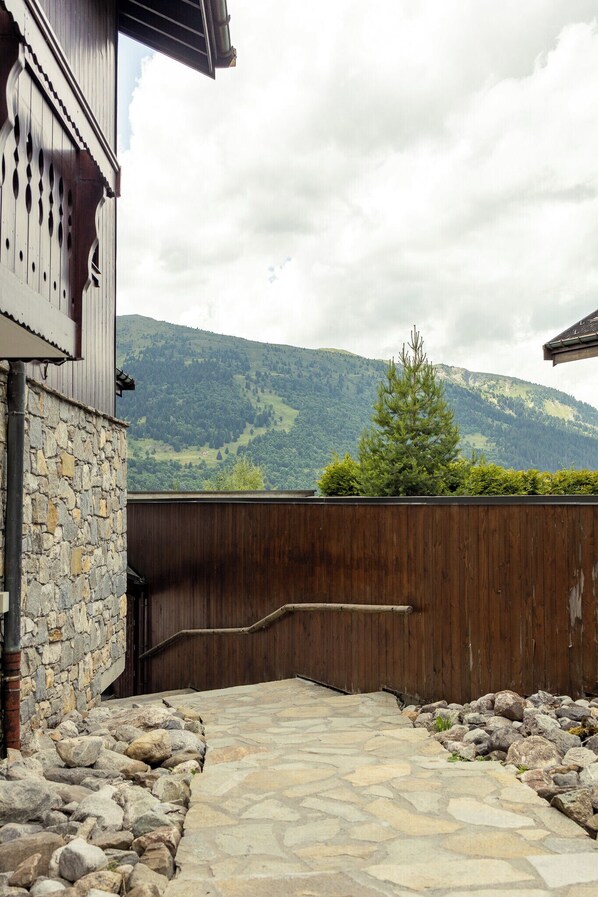 A stone pathway leading to a wooden gate with a mountain view in the background.