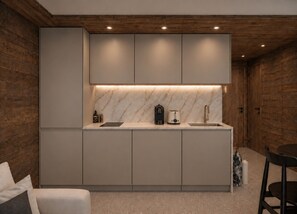 A modern kitchen with built-in cabinets, a marble backsplash, and a central island with a sink and a coffee maker.