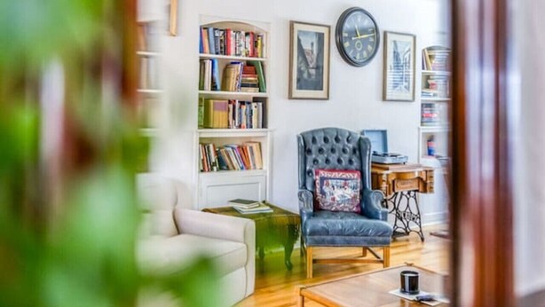 A living room with a sofa, armchair, coffee table, and bookshelf. - Enchanting 2BR in Old Southwest (Reno)
