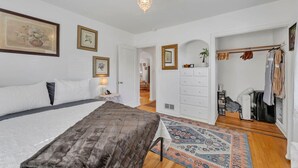 A bedroom with a bed, a nightstand, a dresser, a mirror, and a door leading to a hallway. - Enchanting 2BR in Old Southwest (Reno)
