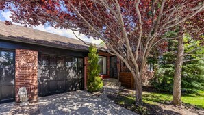A residential house with a garage, a brick exterior, and a well-maintained lawn. - Enchanting 2BR in Old Southwest (Reno)