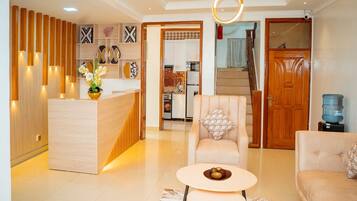 Un salon moderne avec un comptoir d’accueil en bois, un canapé, une table basse et un coussin à motifs.