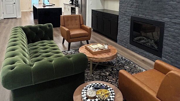 Una sala de estar moderna con un sofá verde, un sillón marrón y una mesa de centro con un objeto decorativo.