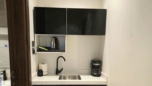 A compact kitchen with a sink, a coffee maker, and a kettle on the countertop. -  فايان استديو مودرن بسرير مزدوج وصالة ودخول ذكي في المنطقة الحية في شمال بريدة (Buraydah)