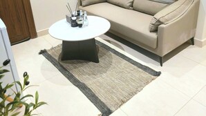 A modern living room with a beige sofa, a round coffee table, and a small rug. -  فايان استديو مودرن بسرير مزدوج وصالة ودخول ذكي في المنطقة الحية في شمال بريدة (Buraydah)