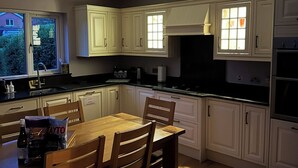 A modern kitchen with white cabinets, a dining table with chairs, and a skylight above. - ☘️Spacious Family Home in Belfast (Belfast)