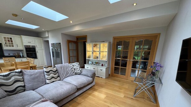 A spacious living area with a large sofa, a dining table, and a kitchen in the background. - ☘️Spacious Family Home in Belfast (Belfast)
