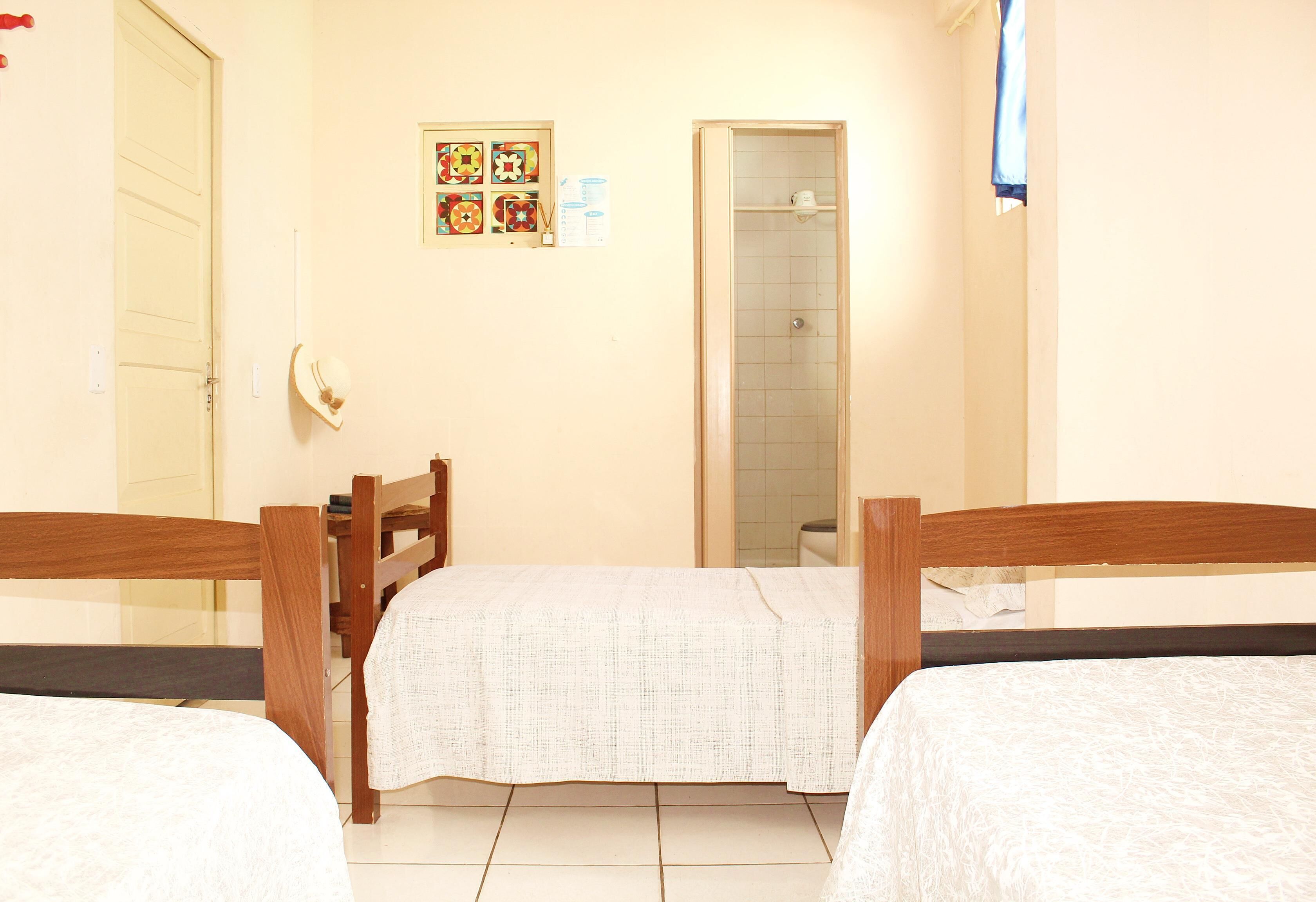 A hotel room with two wooden beds, a shower, and a wall with a bulletin board.