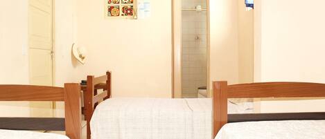 A hotel room with two wooden beds, a shower, and a wall with a bulletin board.