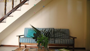 A living room with a striped sofa, a wooden coffee table with magazines, and a vase with green plants. - Sopro de Iemanjá Hostal (Salvador)