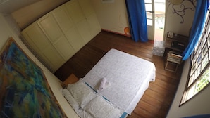 A room with a bed, a window with curtains, a door, and a wall with a decorative pattern. - Sopro de Iemanjá Hostal (Salvador)