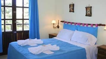 Una cama bien hecha con ropa de cama azul y blanca, un cabecero de madera y una mesita de noche con una lámpara.