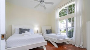 A bedroom with two beds, a ceiling fan, and a large window with curtains. - Amazing 6 Bedrooms With Pool (Kissimmee)