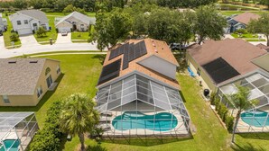 A residential area with houses, a swimming pool, and a clear sky. - Amazing 6 Bedrooms With Pool (Kissimmee)