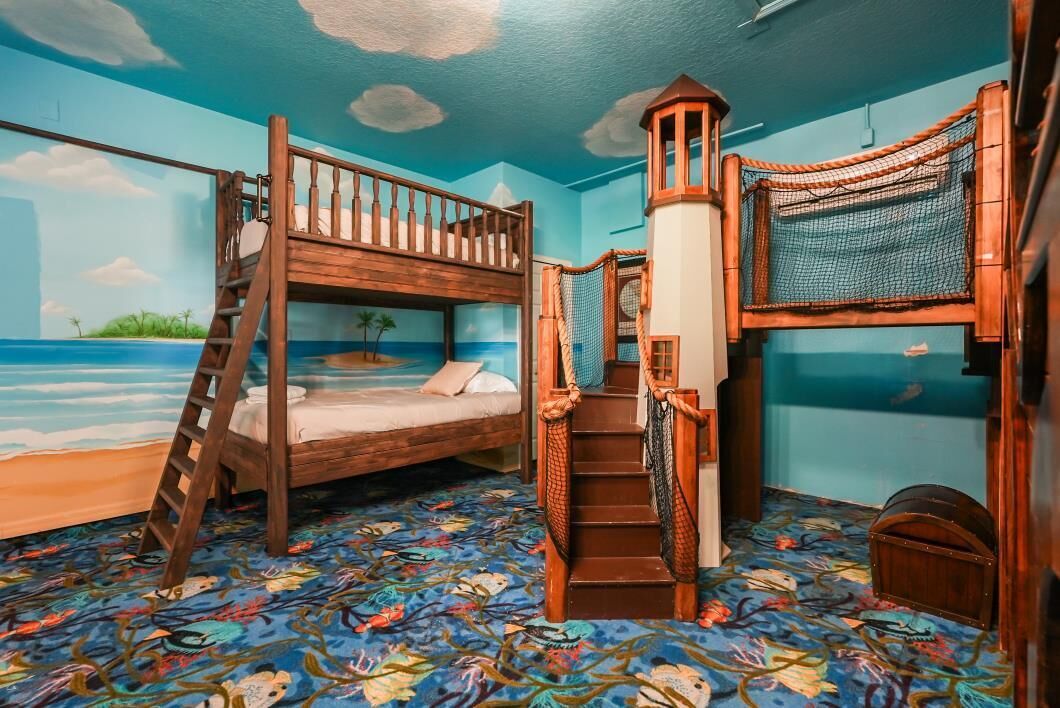 Ein Zimmer mit einem Etagenbett, einer Leiter, einer Treppe und einem Spielbereich mit Netz.