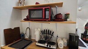 A compact kitchen with a microwave, coffee maker, and a sink. - The Glamp Inn (Lincolnton)