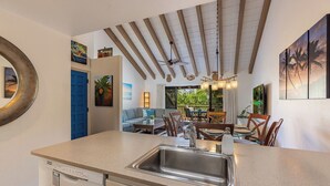 Une cuisine compacte dotée d’un lave-vaisselle intégré, d’un coin repas avec une table et des chaises, et d’un ventilateur de plafond.