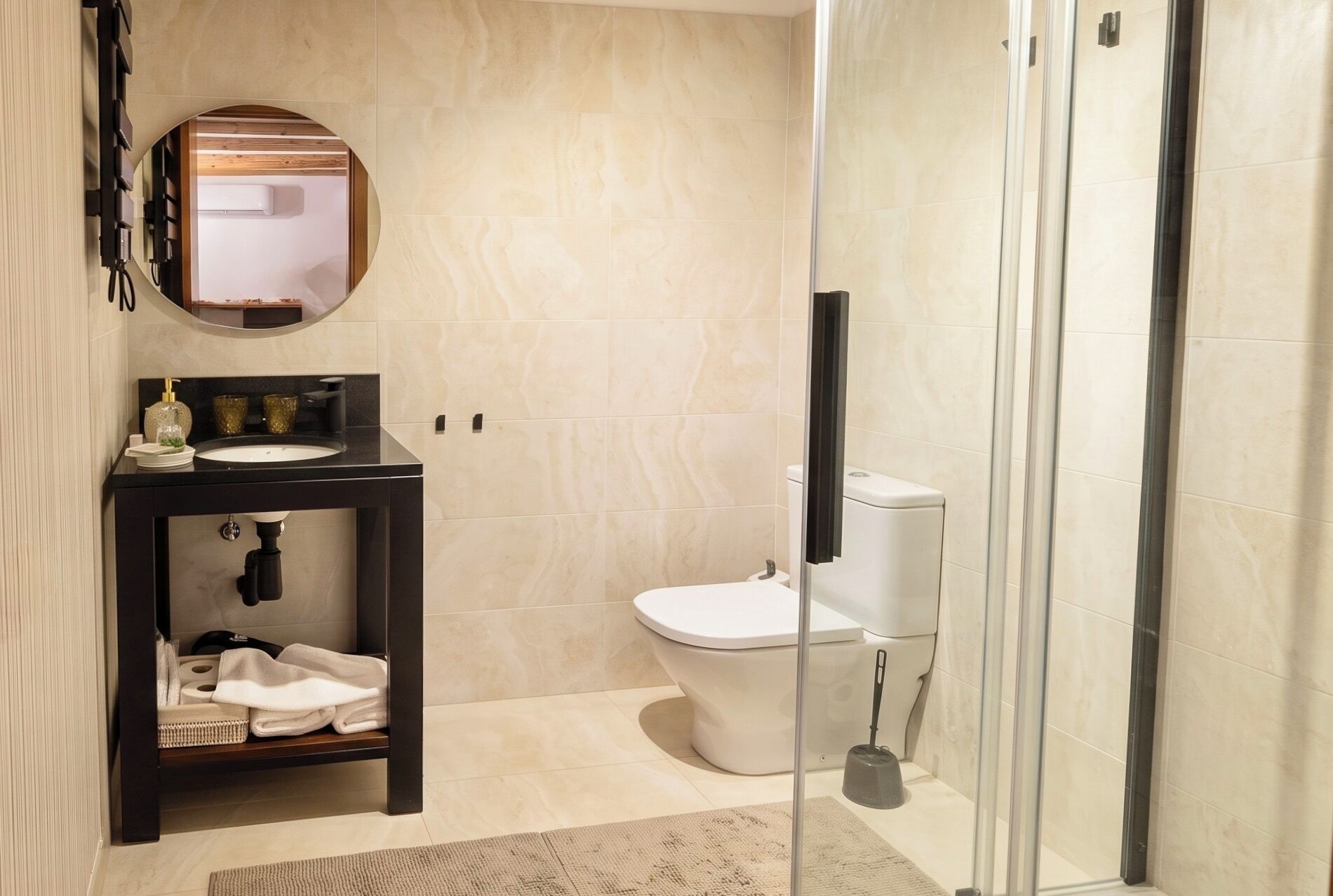A modern bathroom with a sink, toilet, and glass shower enclosure.