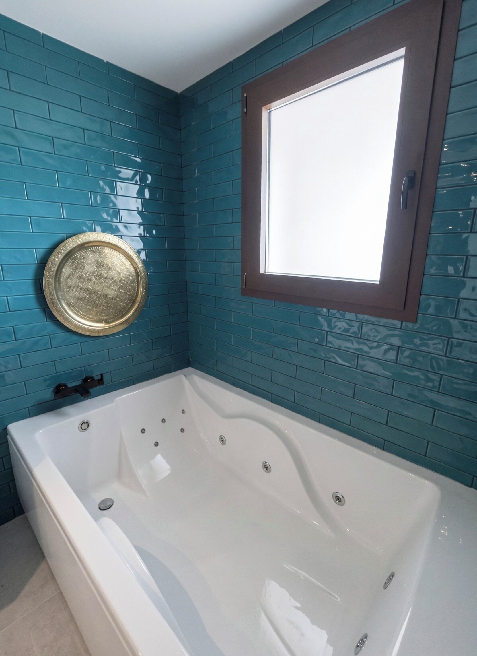 A bathroom with a bathtub, a window, and a decorative plate on the wall.