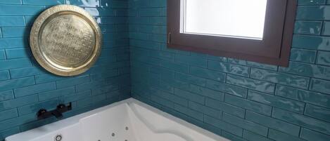 A bathroom with a bathtub, a window, and a decorative plate on the wall.