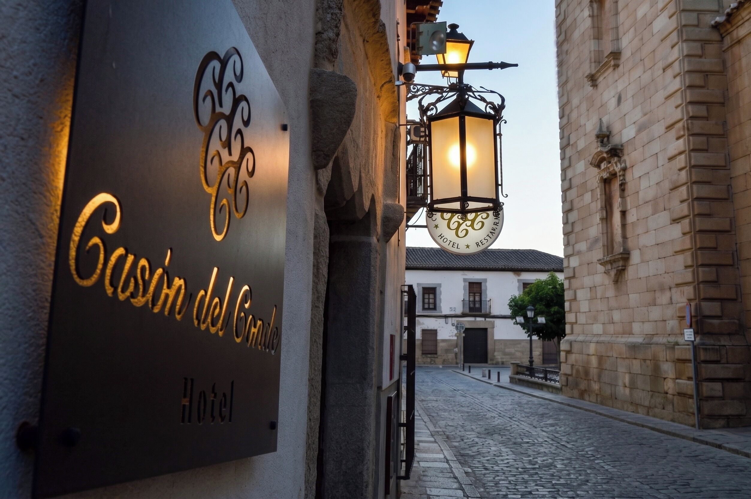 A sign for 'Casa del Gordo Hotel' with a cobblestone street and historic buildings in the background.