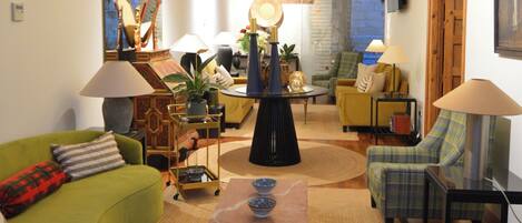 Una sala de estar con un sofá verde, una mesa de centro y un sillón amarillo. Hay una chimenea, un televisor y un espejo en la pared.