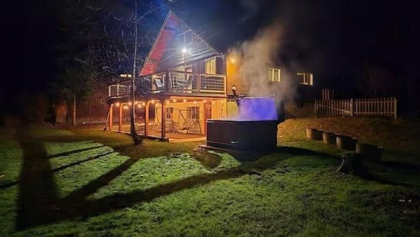 Une maison avec un jacuzzi dans le jardin, la nuit.