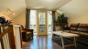 Un vaste espace de vie doté d’un plancher en bois, d’un canapé, d’une table basse et d’un escalier.