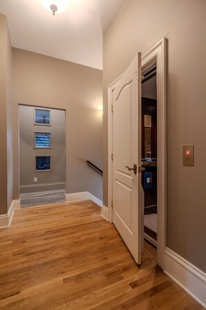 Ein Korridor mit Holzboden, einer weißen Tür zu einem Schrank und einer Treppe im Hintergrund.