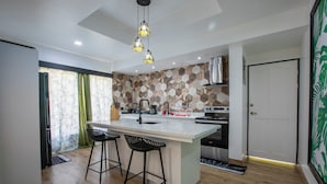 Una cucina moderna con isola centrale, sgabelli da bar e zanzariera decorata.