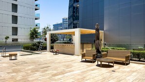 An outdoor patio area with a wicker sofa, a small round table, and a covered seating area. - Stylish Studio at DAMAC Majestine (Dubai)