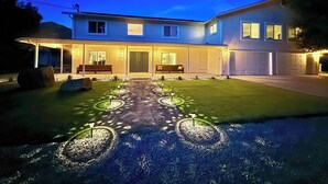 Une maison moderne à deux étages, dotée d’un patio couvert et d’une allée bien éclairée.
