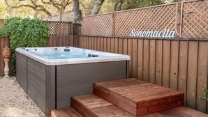 A hot tub with wooden steps leading up to it, surrounded by a wooden fence and a sign that reads "Sonomacita".