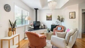 A modern living room with a fireplace, a clock, and a chandelier.